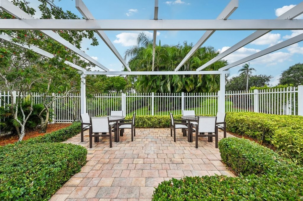 A patio with a white pergola and a table set for four.