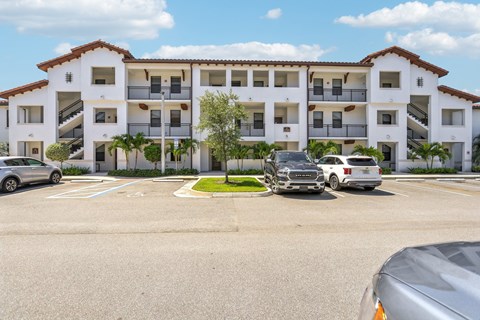 A white apartment building with a parking lot in front.
