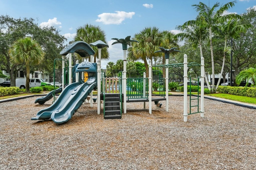A playground with a green slide and a yellow sign.