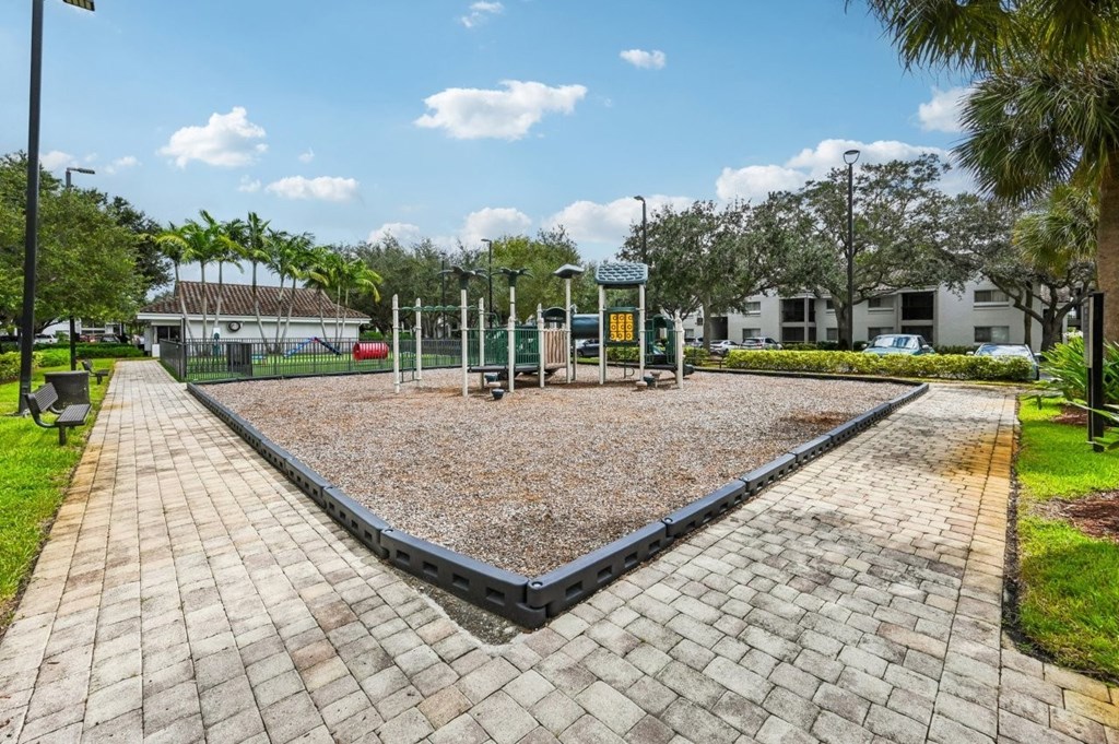 A playground with a yellow signboard and a black fence.