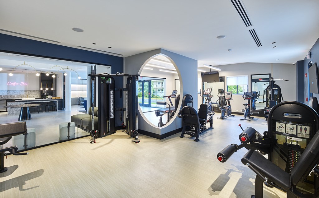 a large fitness room with cardio machines and weights