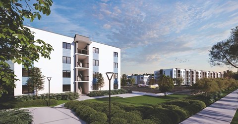 A modern apartment complex with a well-maintained lawn and trees.