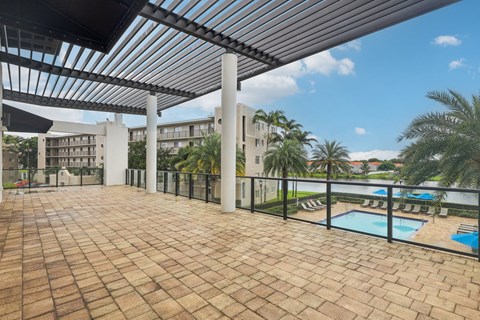 A patio with a pool and a building in the background.