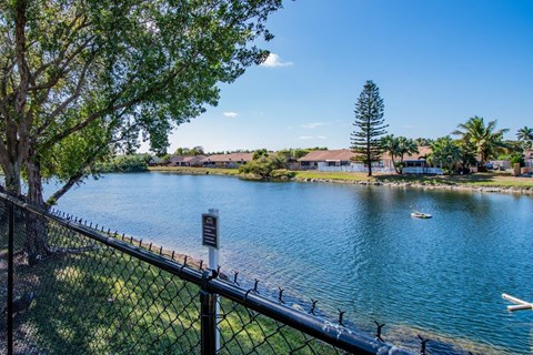 a view of a lake with a fence and a boat in it