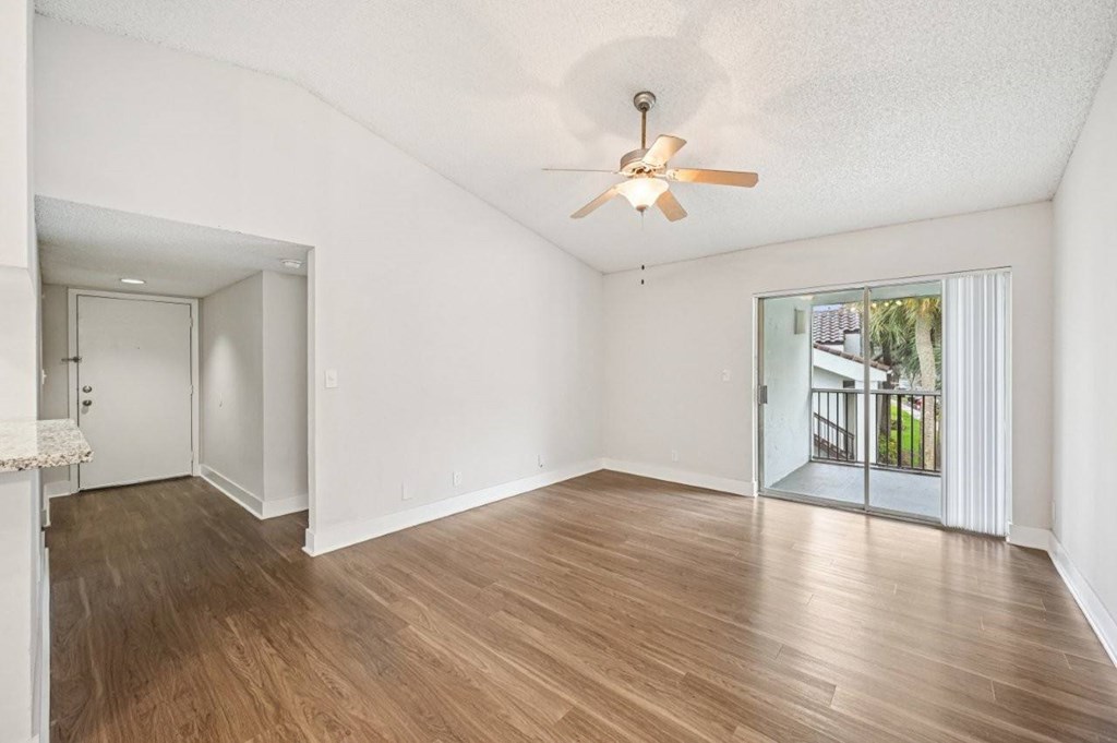 A room with a ceiling fan and wooden flooring.
