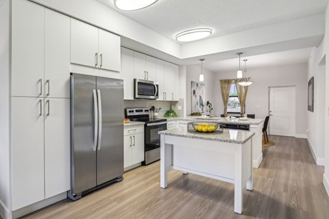 A kitchen with a refrigerator, microwave, and oven.