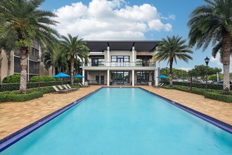 A large swimming pool in front of a building surrounded by palm trees.