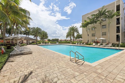 A swimming pool surrounded by palm trees and lounge chairs.