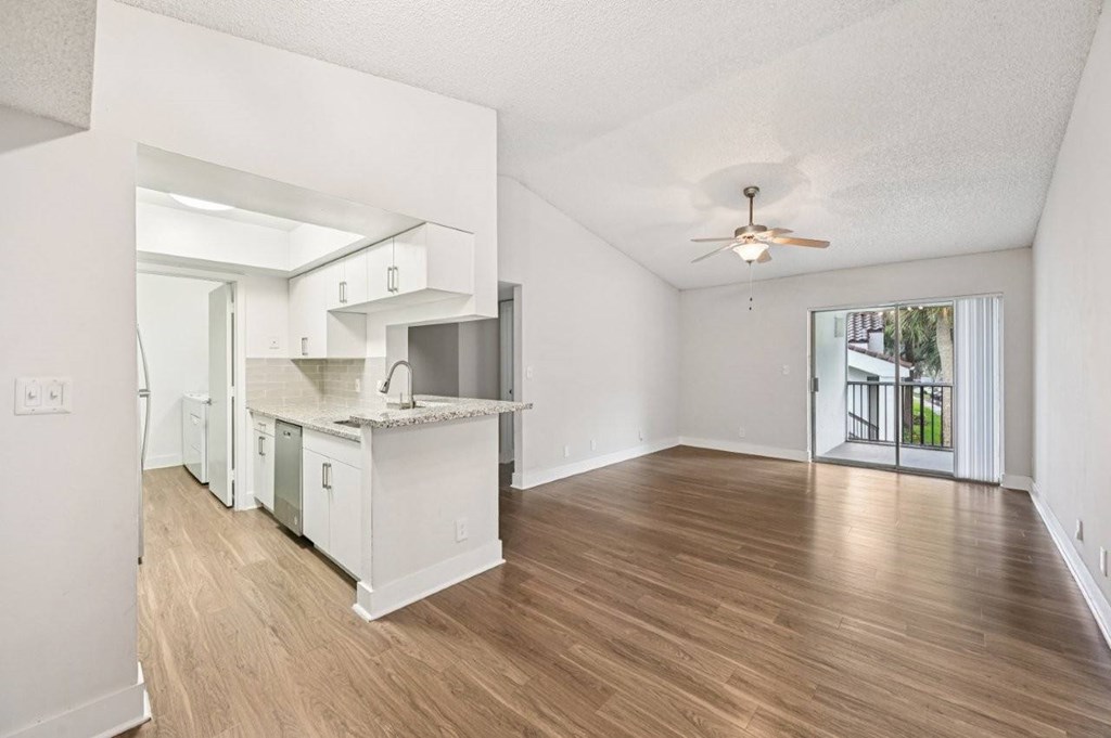 A spacious kitchen with white cabinets and a marble countertop.