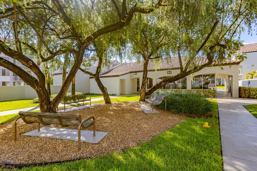a park with benches and trees in front of a building