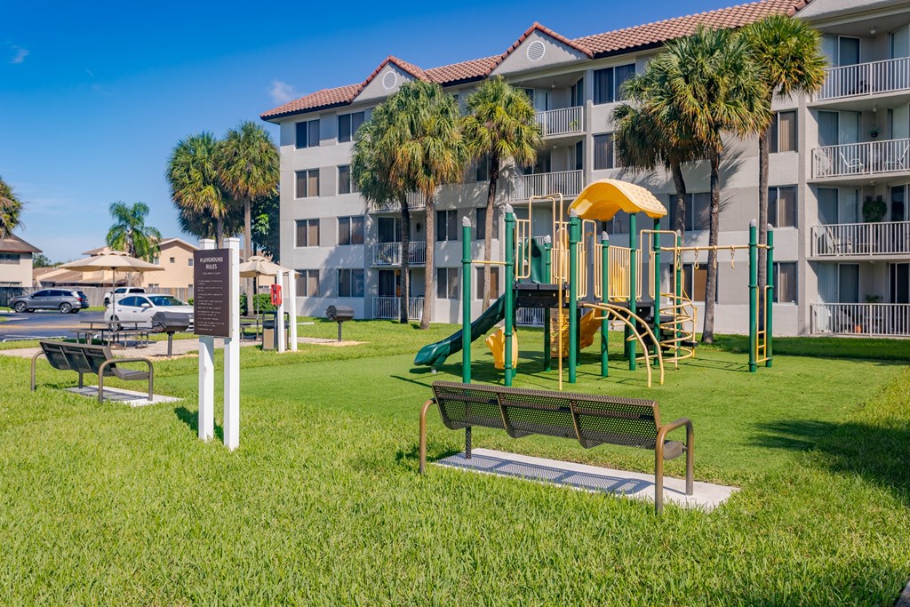 a park with a playground in front of a hotel