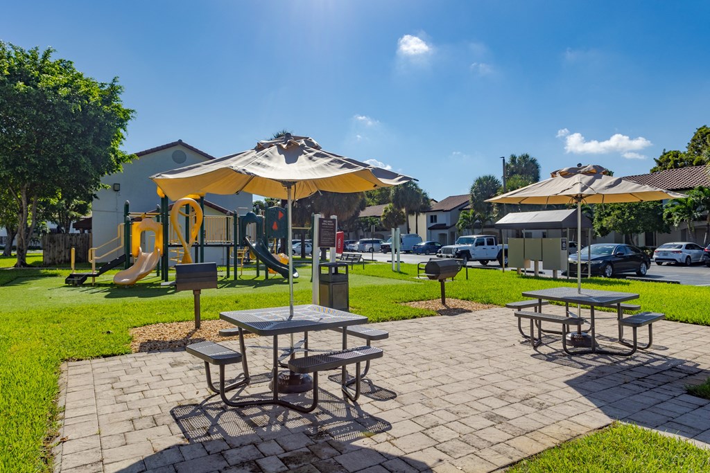 a picnic area with tables and umbrellas in a park