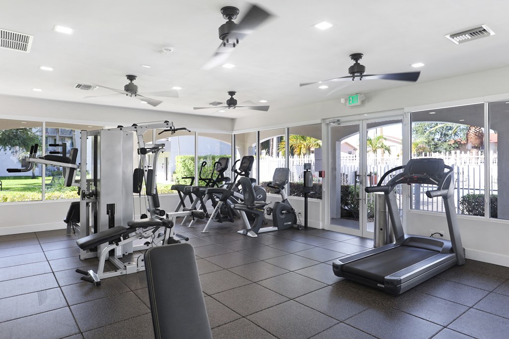a gym with weights and other equipment in a building with windows