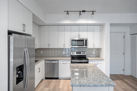 a kitchen with white cabinets and granite counter tops and stainless steel appliances
