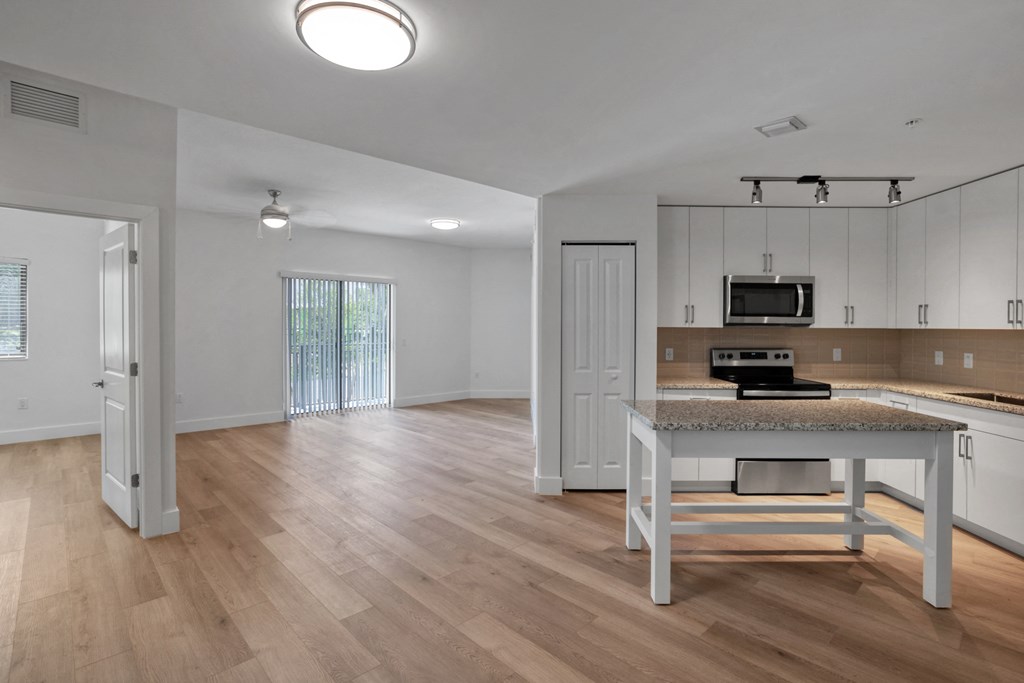 an open living room and kitchen with a door that leads to a balcony