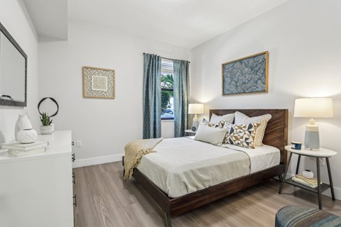 A bedroom with a large bed and a nightstand with a lamp.