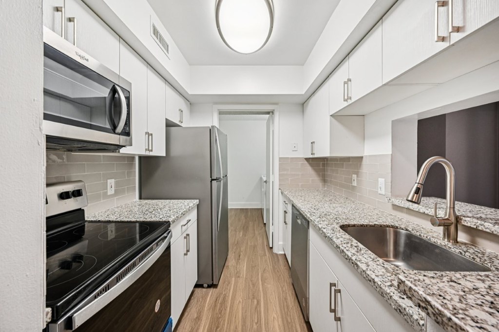 A kitchen with a refrigerator, oven, and sink.