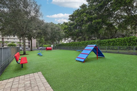 A playground with a red slide and a red bench.