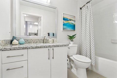 A white bathroom with a toilet, sink, and a mirror.