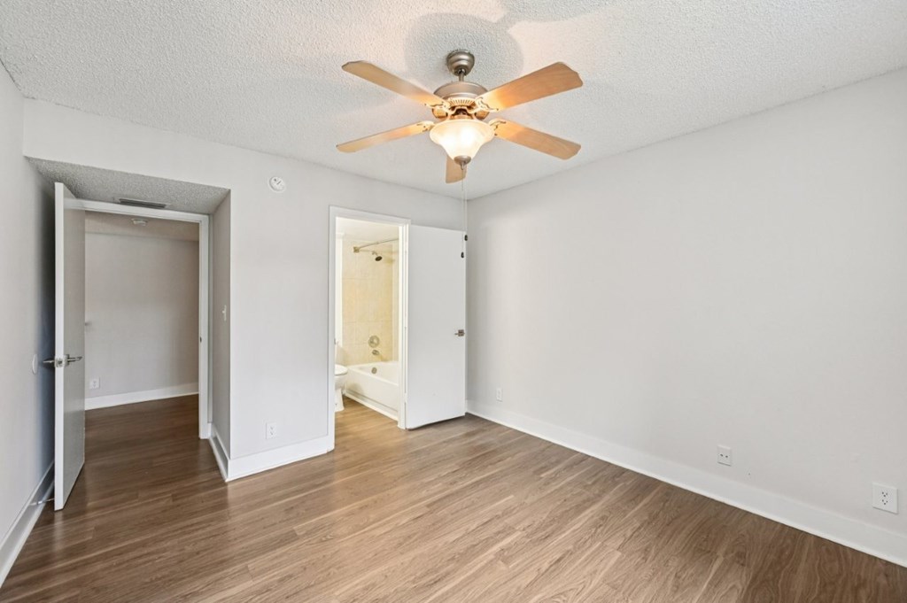 A room with a ceiling fan and wooden floors.