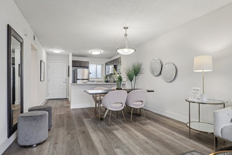 A modern dining room with a wooden floor and white walls.