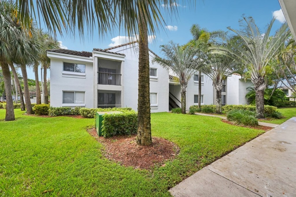 A white building with a green bush in front of it.
