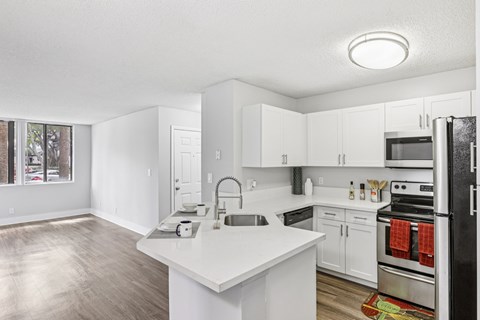 A kitchen with white cabinets and a black refrigerator.