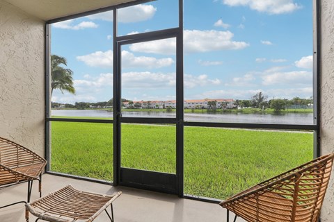 A patio with a chair and a table is overlooking a grassy field.