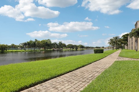 A walkway runs parallel to a body of water with a building on the right.