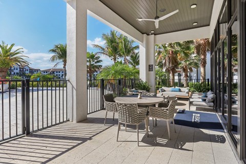 A patio with a table and chairs overlooking a pool.