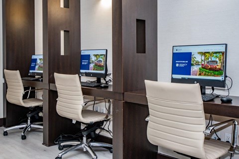 three computer desks in a room with white chairs