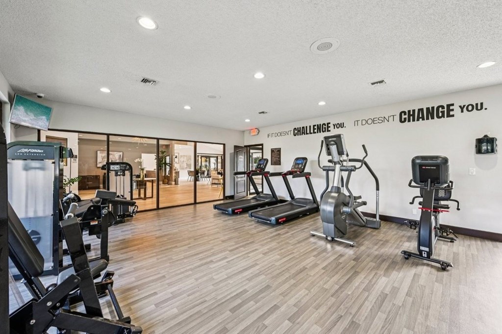 A gym with a variety of equipment including treadmills, stationary bikes, and weight machines.