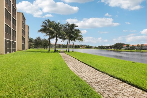 A walkway leads through a grassy area next to a body of water.