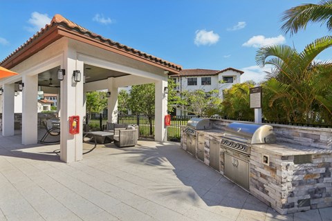 A patio with a stone wall and a grill.