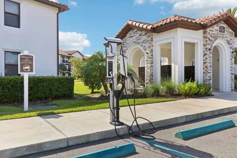 A charging station for electric vehicles is located on the sidewalk in front of a building.