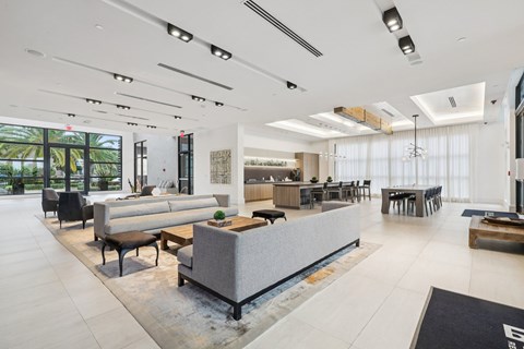 A spacious living room with a grey sofa and a black rug.