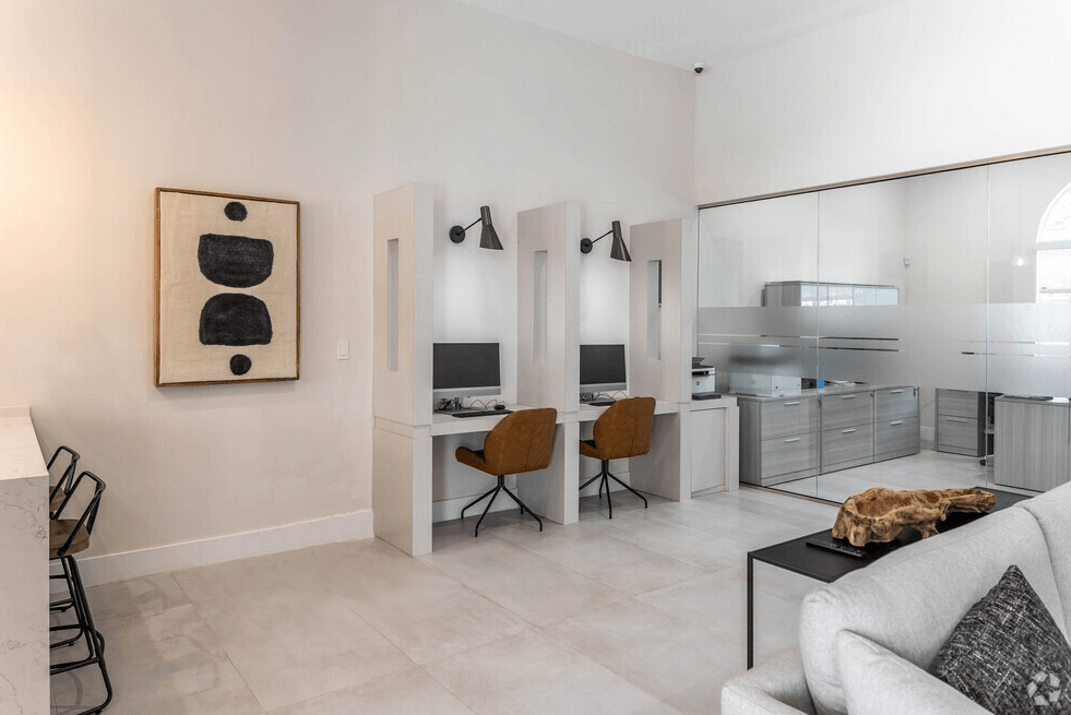 a living room with a couch and a desk and a kitchen