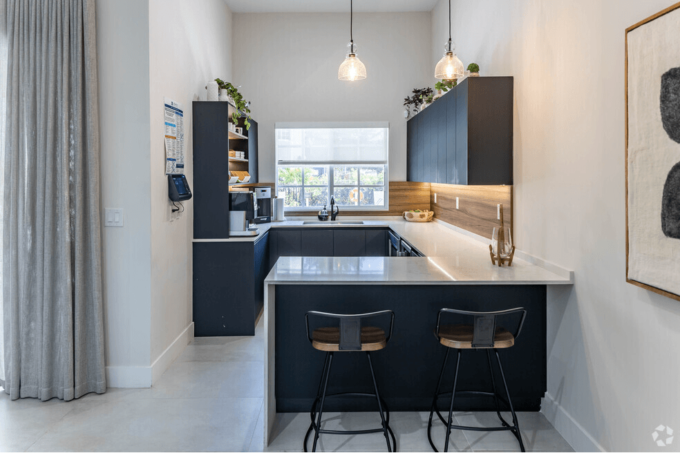 a kitchen with black cabinets and a counter top and two stools