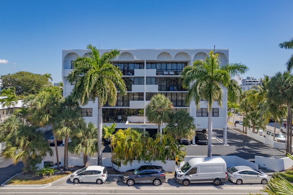 a building with palm trees and cars parked in front of it
