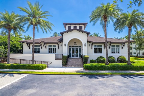A white building with a black roof and palm trees in front.