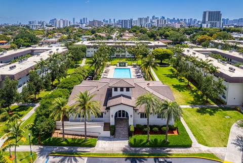A large house with a pool surrounded by palm trees.