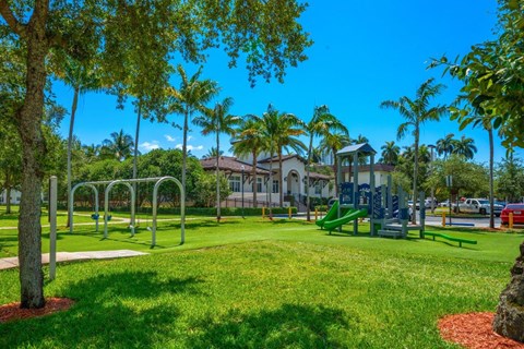 A playground with a green slide and monkey bars.