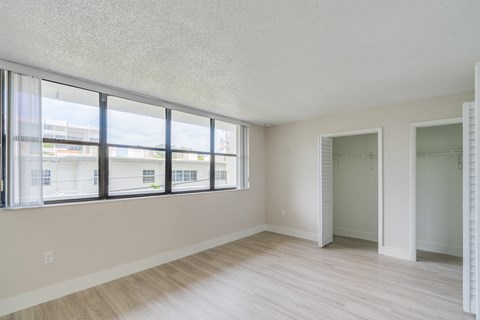 the living room of an apartment with large windows and wood flooring