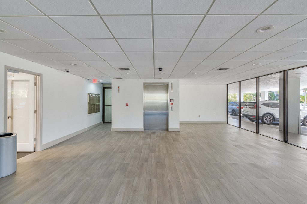 a large room with white walls and wood floors and an elevator