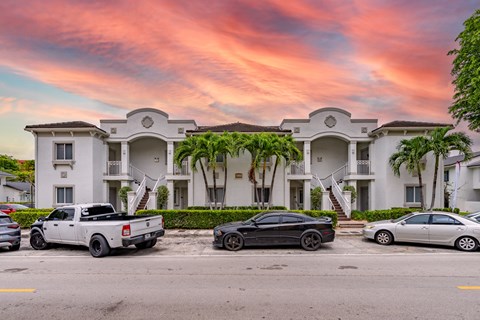 A white building with a black car parked in front of it.