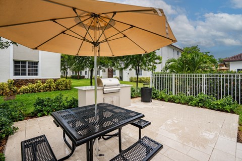 a patio with a table with an umbrella and a grill