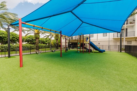 A playground with a blue canopy and a yellow slide.