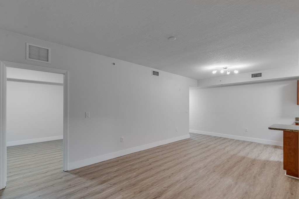 an empty living room with a wood floor and white walls