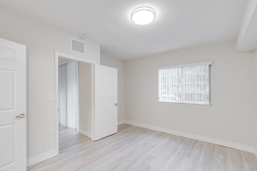 an empty room with a door to a closet and a window