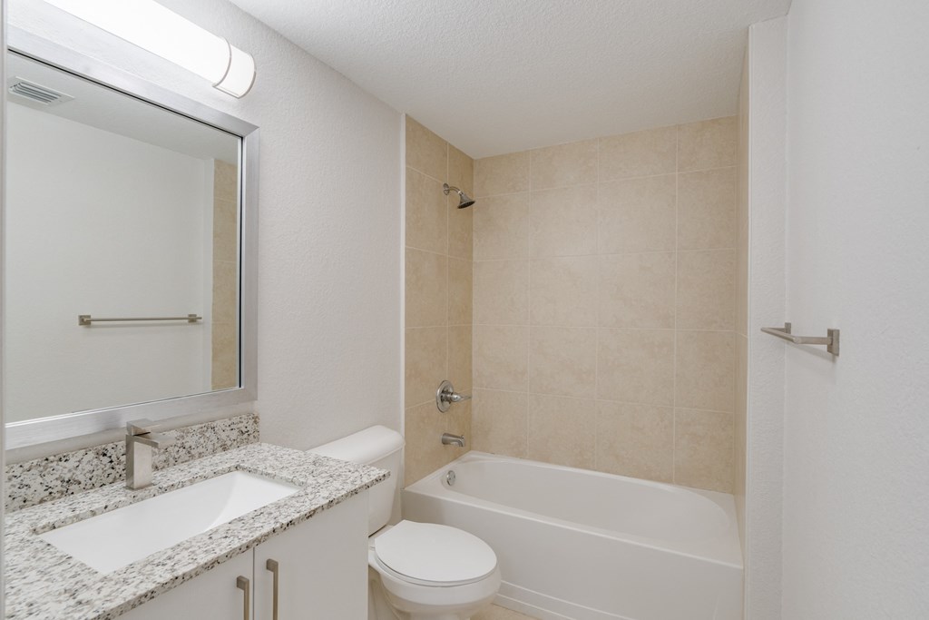 a bathroom with a sink toilet and tub and a mirror